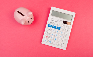 Piggy bank and calculator on color background, top view.