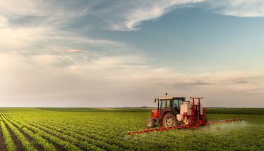 Tractor spraying pesticides at  soy bean fields