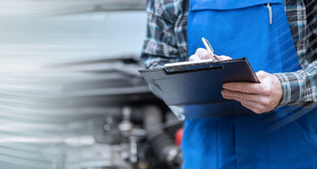 Car mechanic checking a car engine and writing on clipboard; panoramic banner